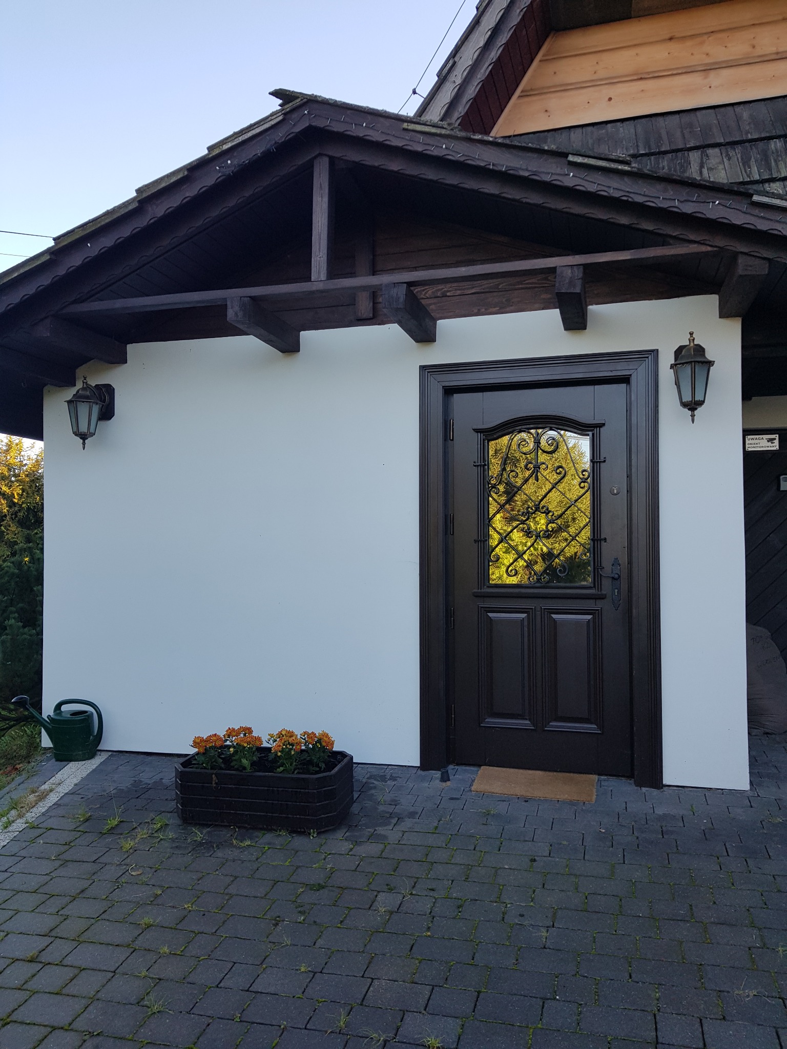 Montaż drzwi drewnianych zewnętrznych z futryną i ozdobną deską okalającą.