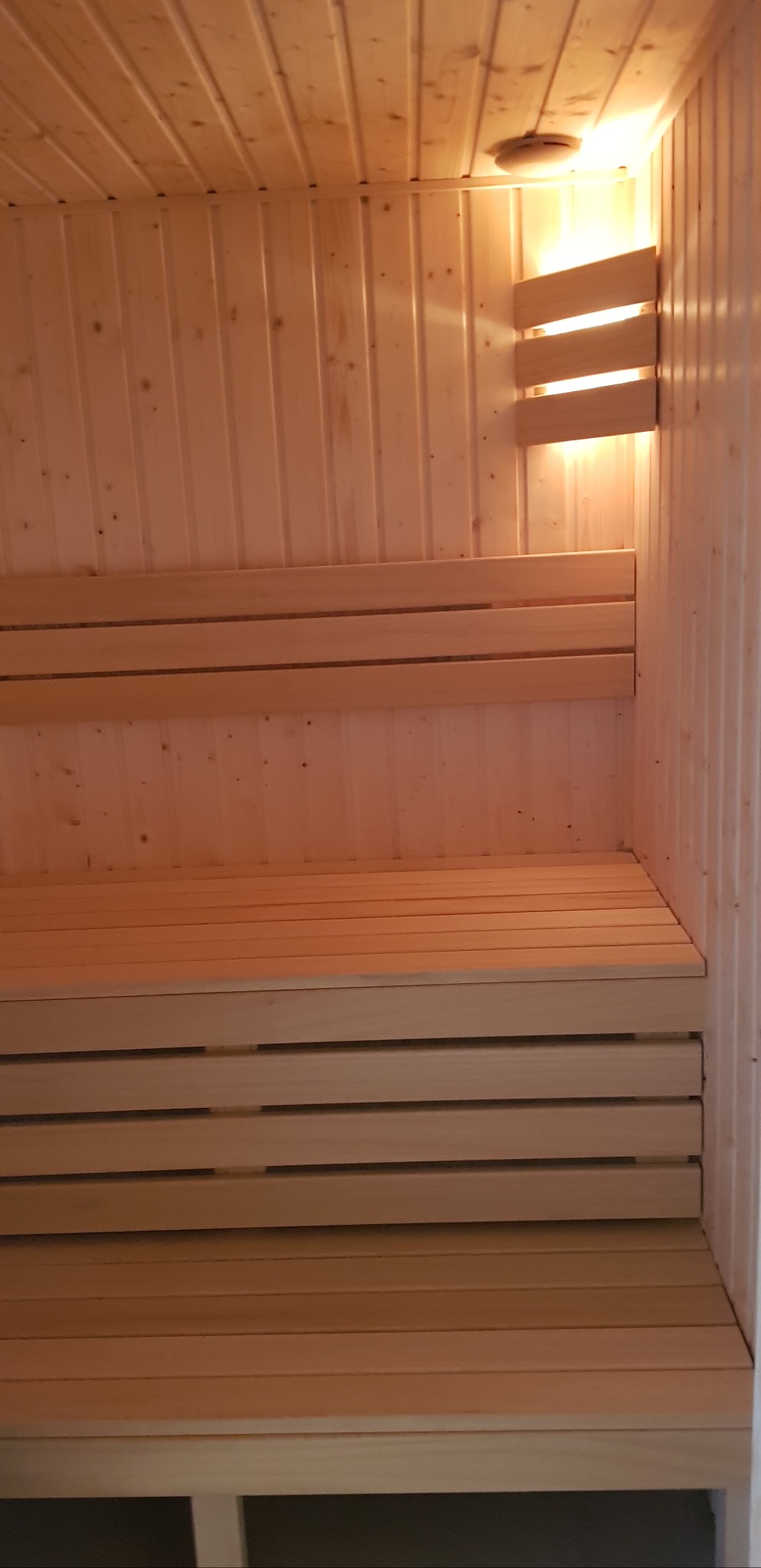 Jasne drewno, z którego zrobiona jest nowa sauna z trzema poziomami ławek i oświetleniem, tworzy przytulną atmosferę.