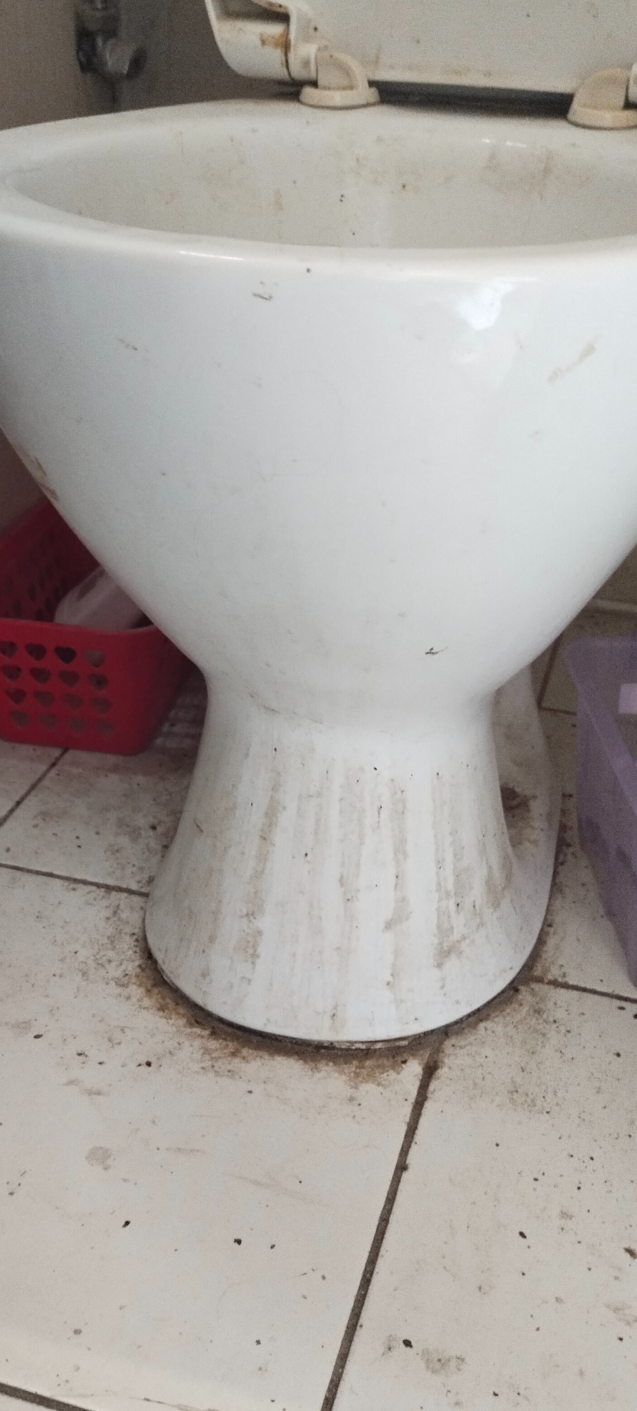 Brudna muszla klozetowa z widocznymi zaciekami i zabrudzeniami na ceramice i podłodze, wymagająca dokładnego czyszczenia.