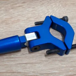 Niebieski, anodowany zacisk mocujący z czarnymi śrubami na drewnianym tle, element konstrukcyjny z aluminium.