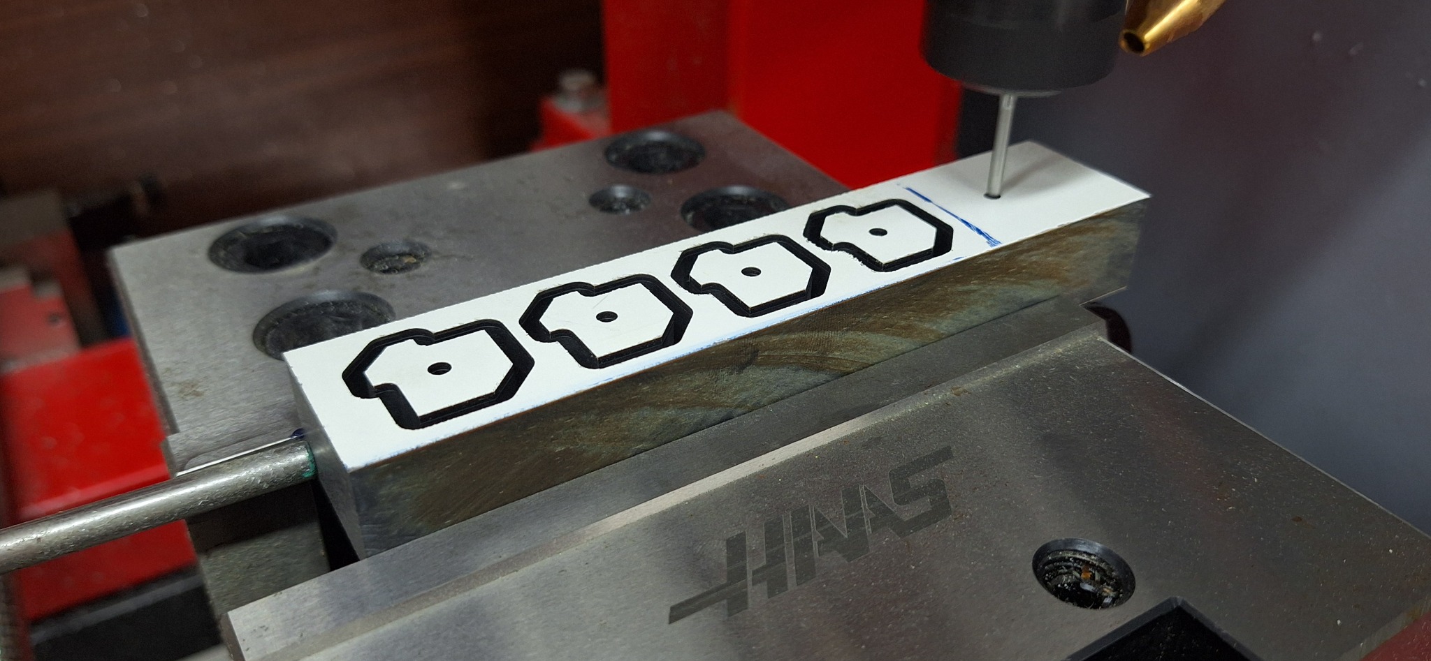 Frezarka CNC w trakcie wycinania powtarzalnych wzorów z białego tworzywa, zamocowanego w uchwycie maszyny.