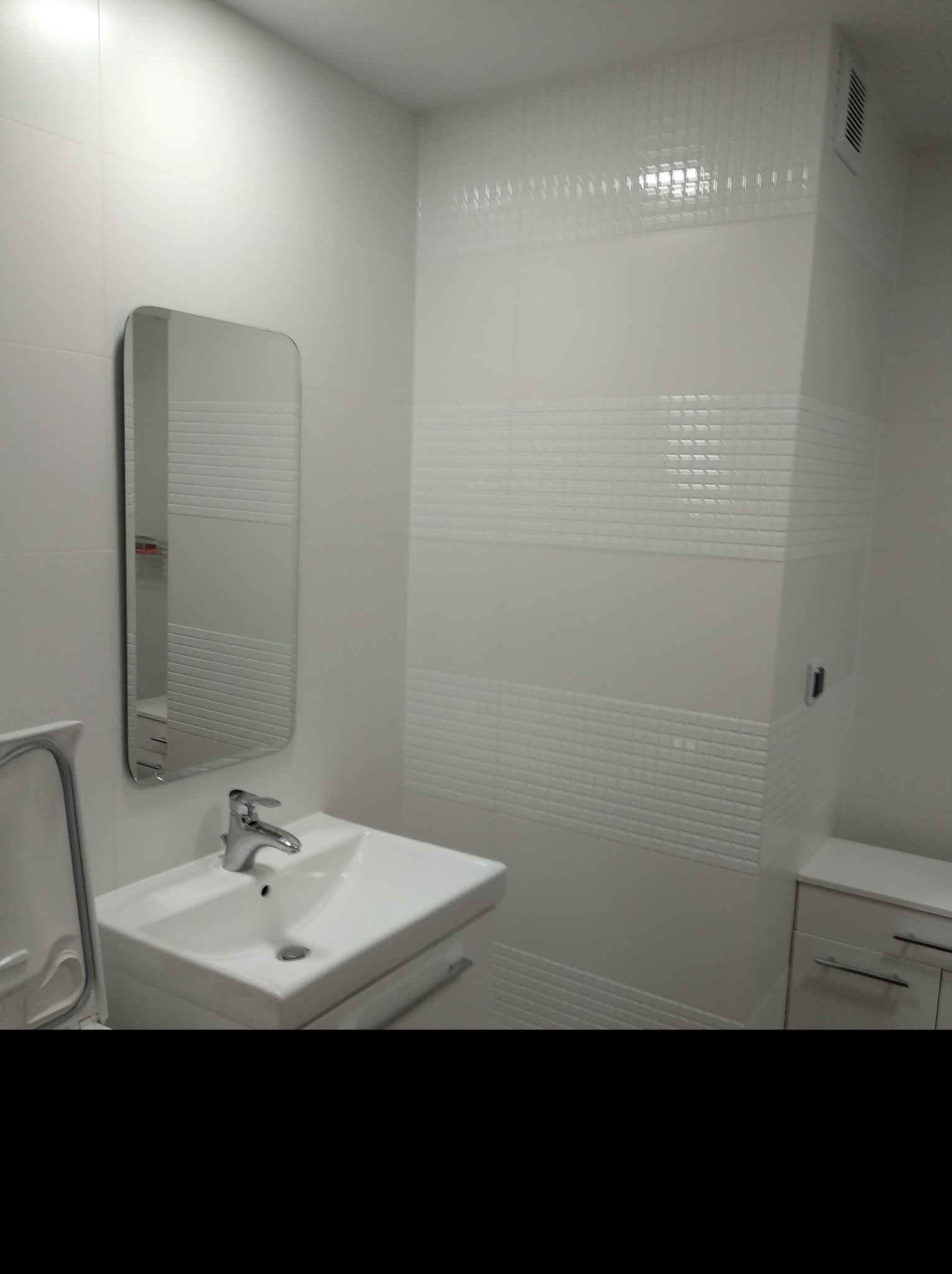 Biała łazienka z umywalką nablatową, lustrem w zaokrąglonej ramie i dekoracyjnymi płytkami w pasy.