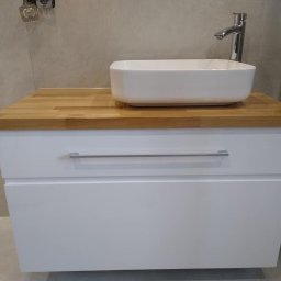 DrewnaMoc - Biała szafka łazienkowa z dwiema szufladami, drewnianym blatem i nablatową umywalką w kształcie prostokąta, chromowana bateria, szare płytki na ścianie.