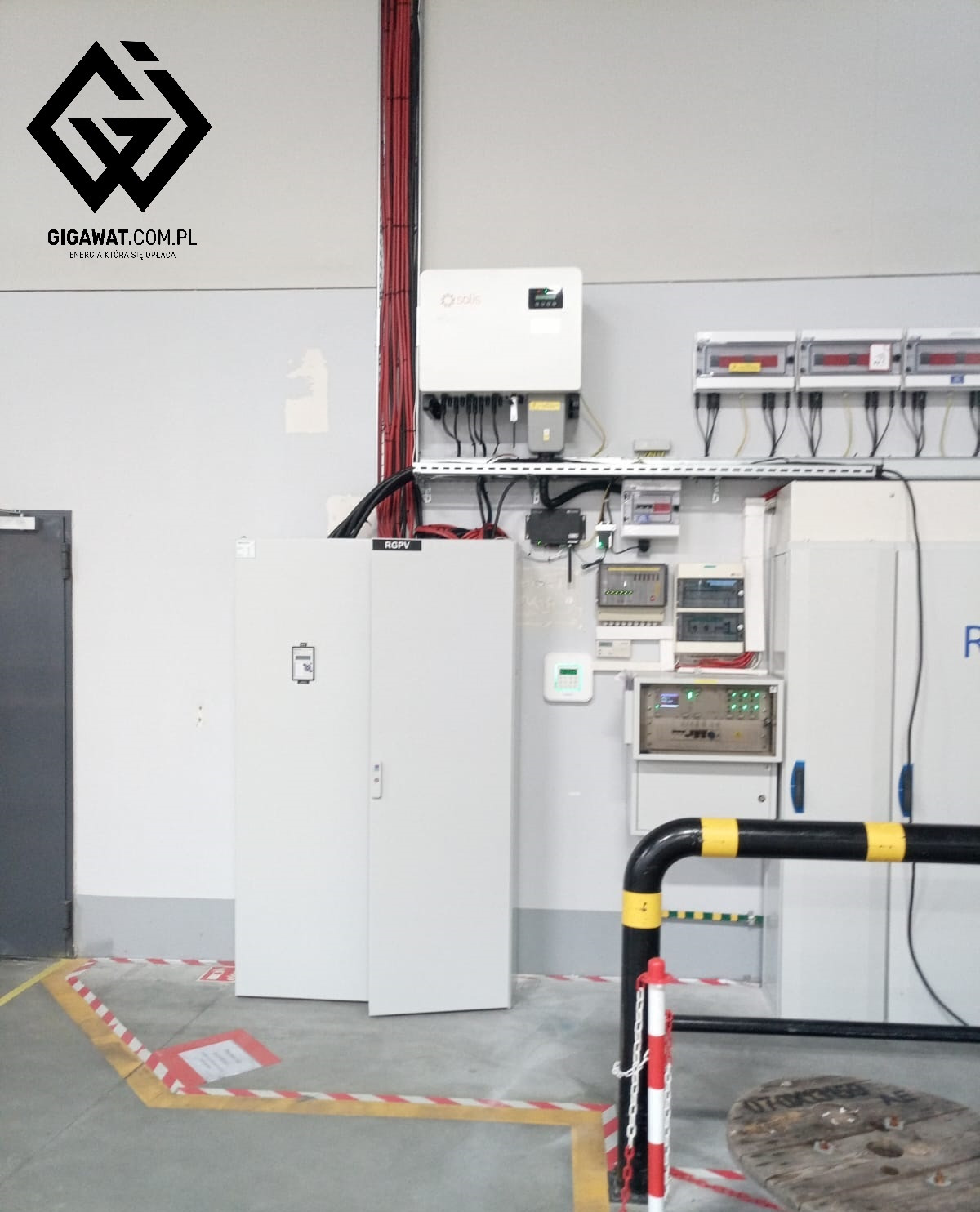 Szafa telemechaniki instalacji 500kW zasilającej obiekt produkcyjny, widoczne okablowanie, falownik Solis, oraz elementy zabezpieczeń elektrycznych w przemysłowym wnętrzu.