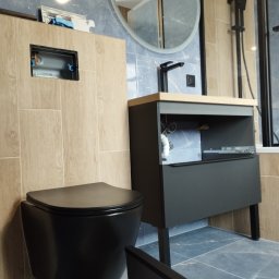 Remont - Nowoczesna łazienka z zabudową toalety podtynkowej w beżowych płytkach imitujących drewno, czarną miską WC i szafką umywalkową w kolorze grafitowym, marmurowe niebieskie płytki na ścianach.