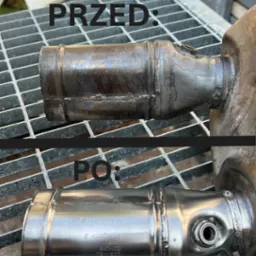 Katalizator samochodowy BMW przed i po piaskowaniu, widoczne różnice w czystości i połysku metalu, umieszczony na metalowej kracie.