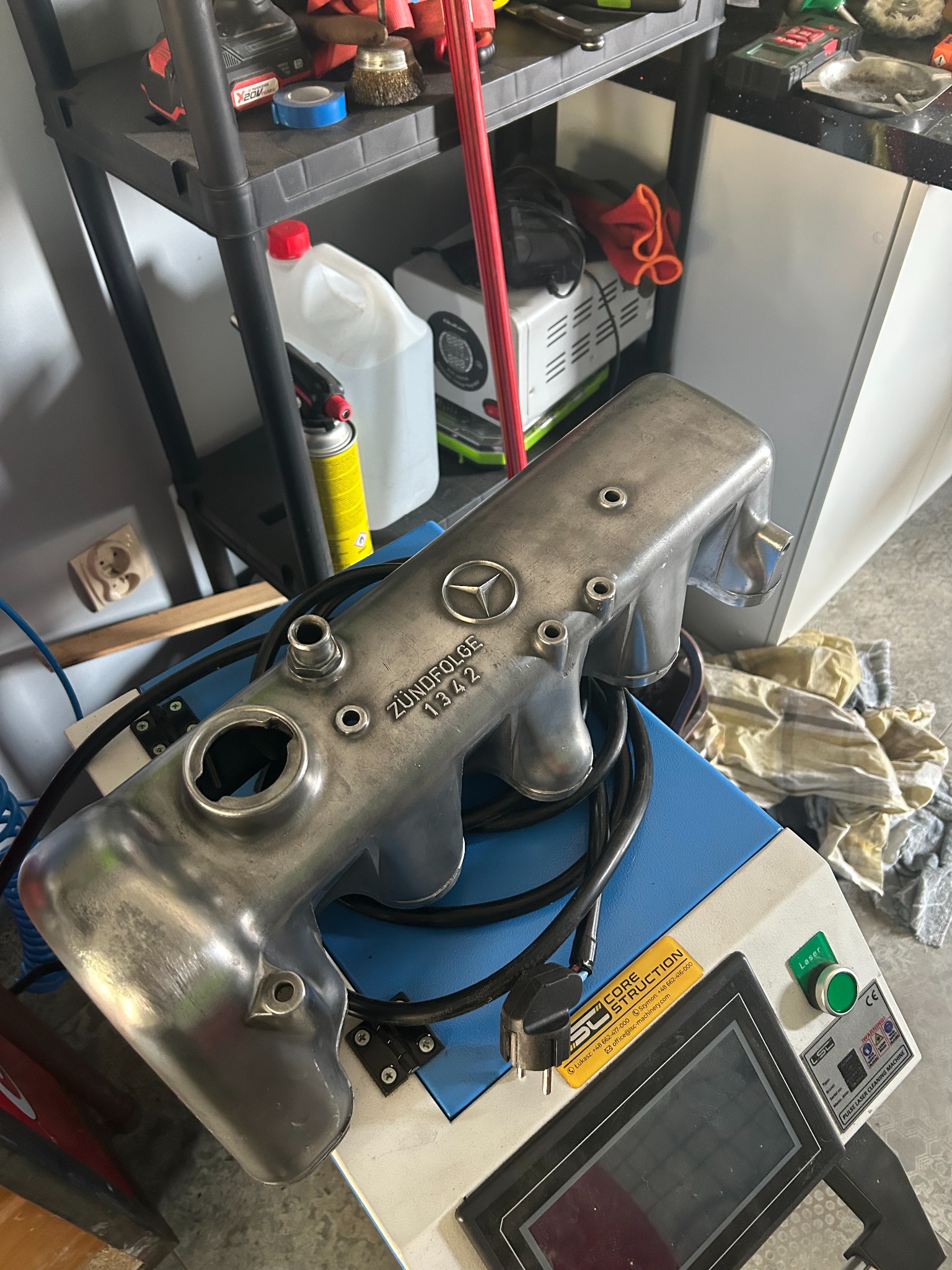 Szczegółowe ujęcie głowicy silnika Mercedes-Benz po piaskowaniu, leżącej na maszynie do czyszczenia laserowego. Widoczny napis ZÜNDFOLGE 1342 i logo Mercedes.