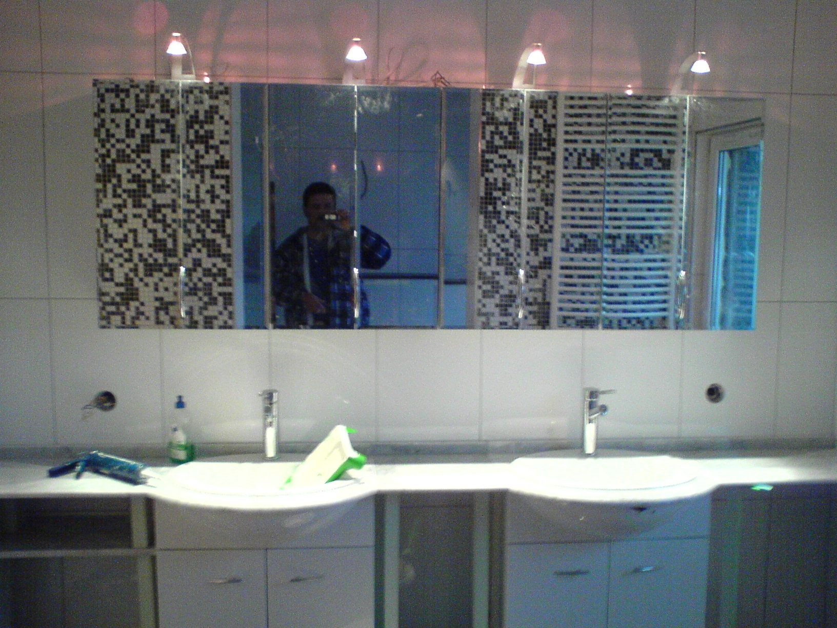 Łazienka z podwójną umywalką i lustrem z mozaiką, widoczne narzędzia i odbicie osoby robiącej zdjęcie.