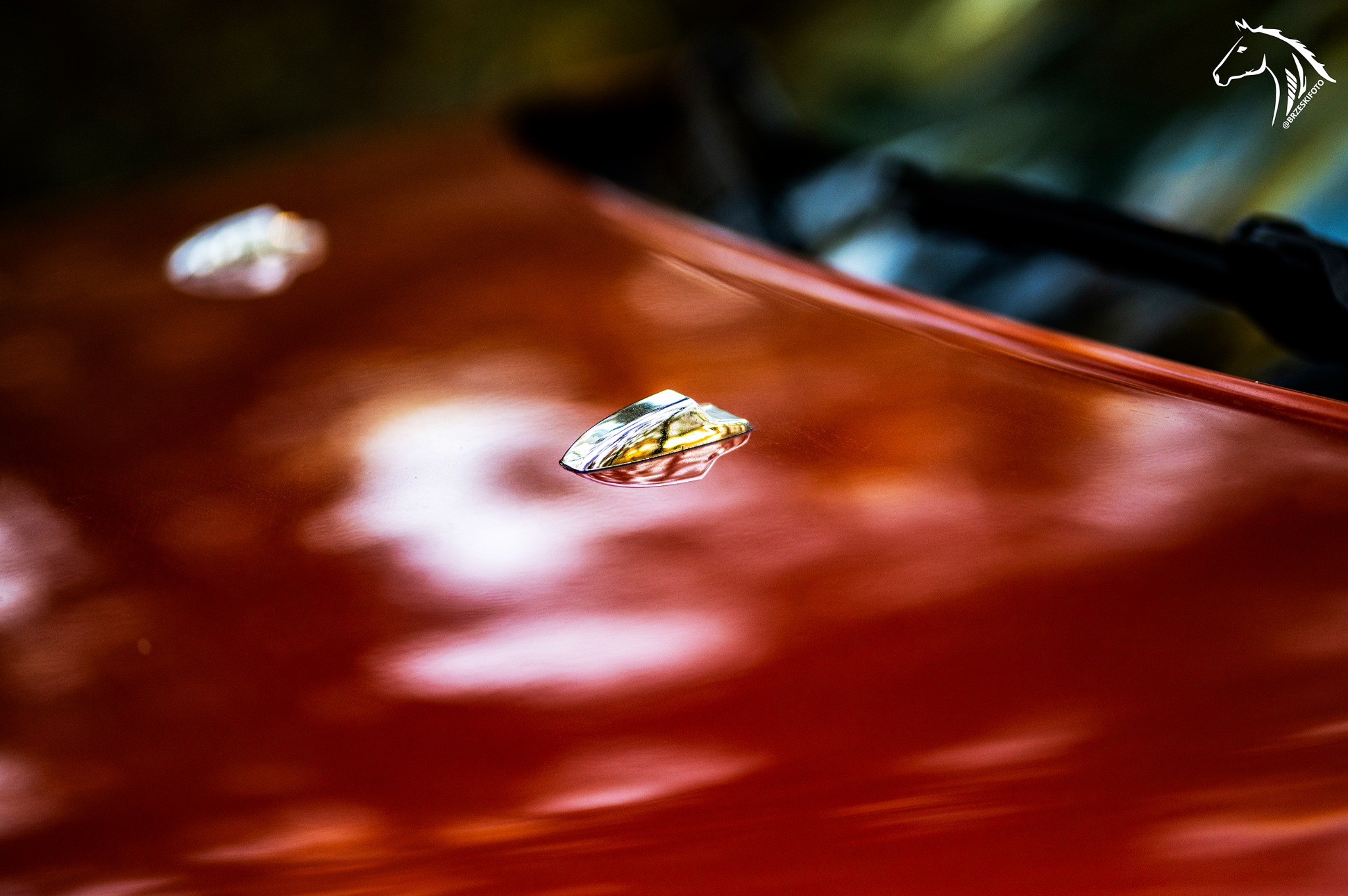 Błyszcząca, czerwona karoseria samochodu z chromowanymi detalami w Wojnowicach, uchwycona w zbliżeniu z refleksami światła.