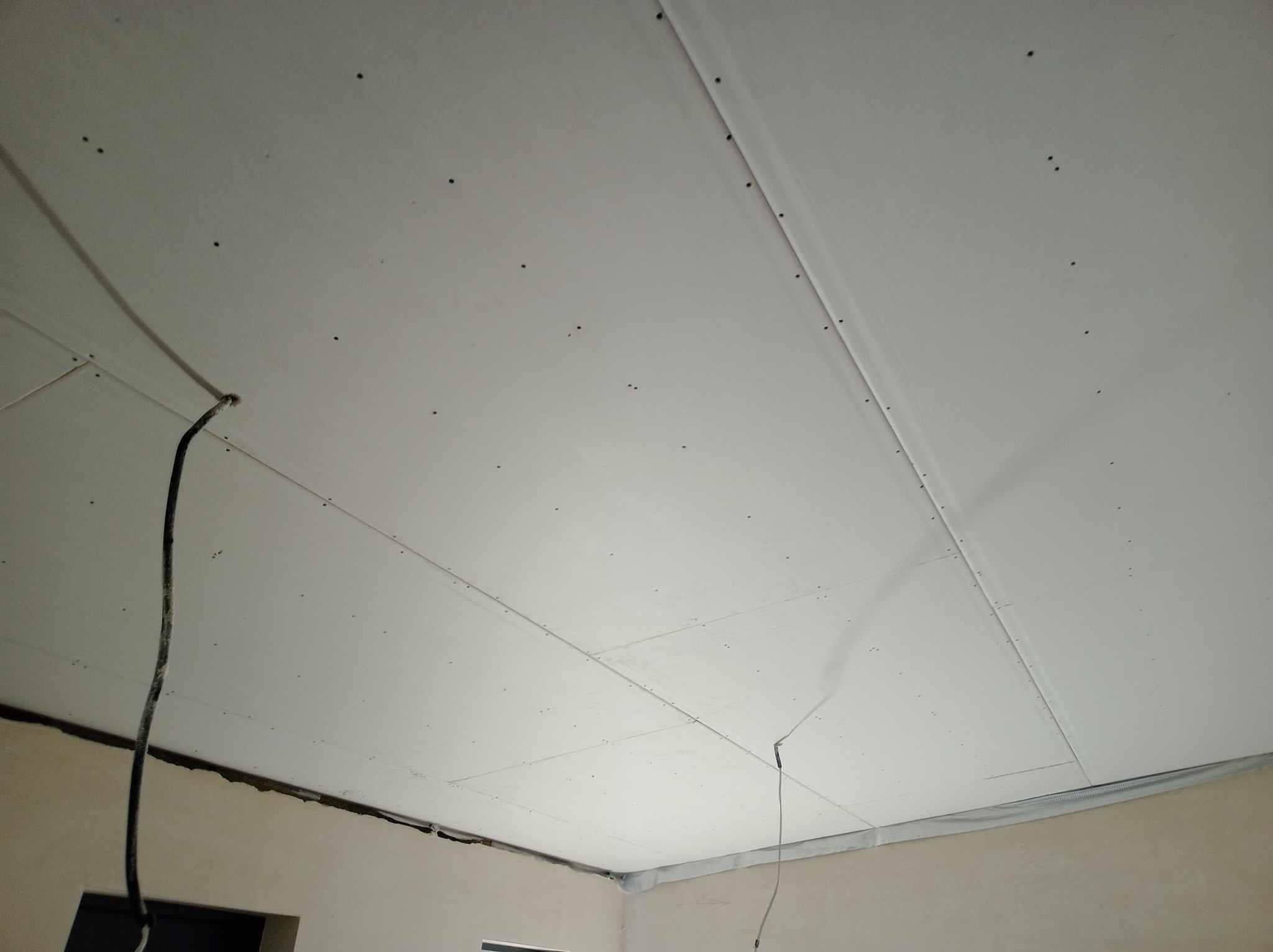 Zamontowany sufit z płyt kartonowo-gipsowych, widoczne łączenia płyt i kable elektryczne w Kiełpinie.