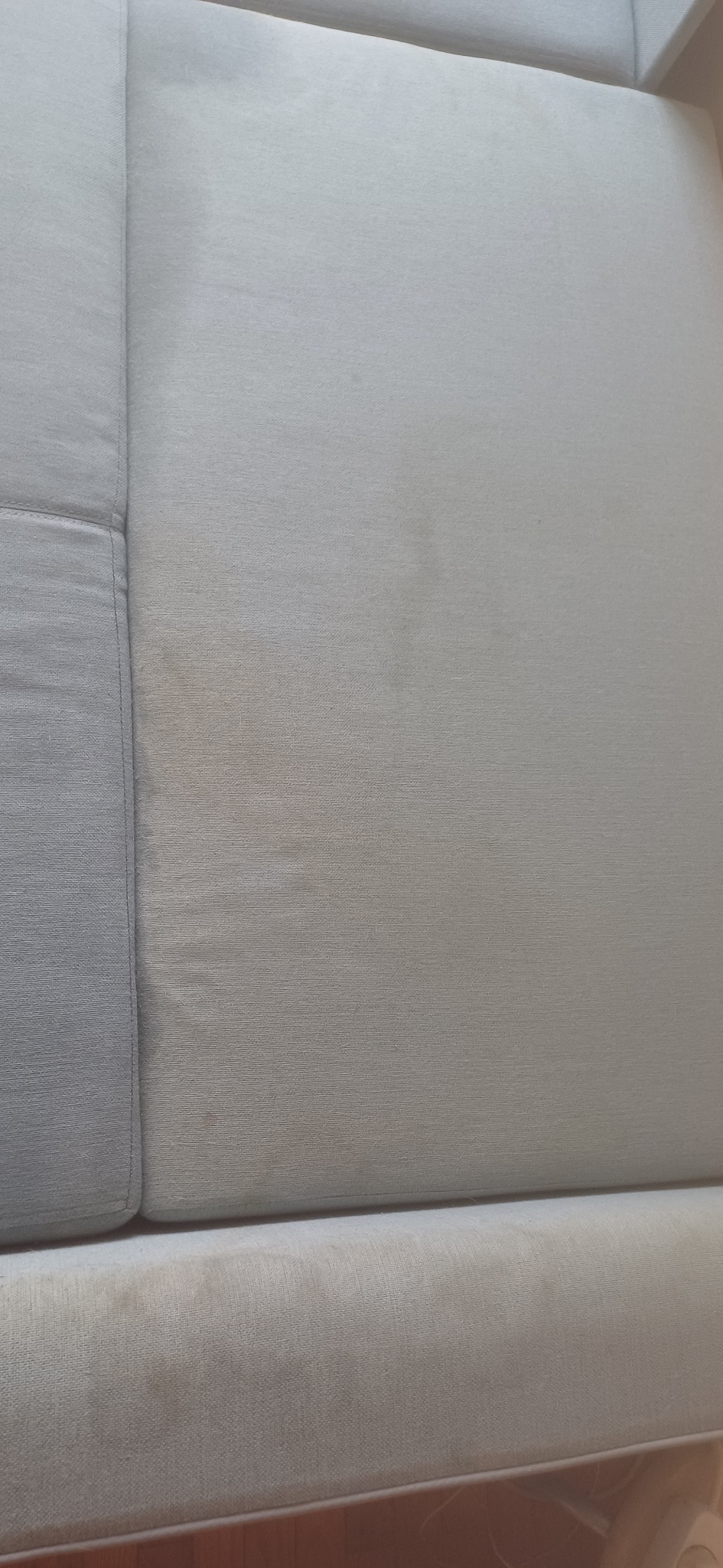 Fragment beżowej kanapy z widocznymi plamami przed praniem tapicerki.