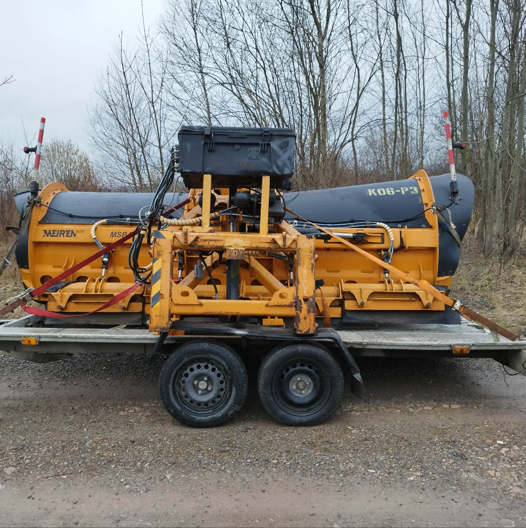 Żółta odśnieżarka MEIREN NEW MSP na przyczepie transportowej, zabezpieczona pasami, na tle drzew bez liści.