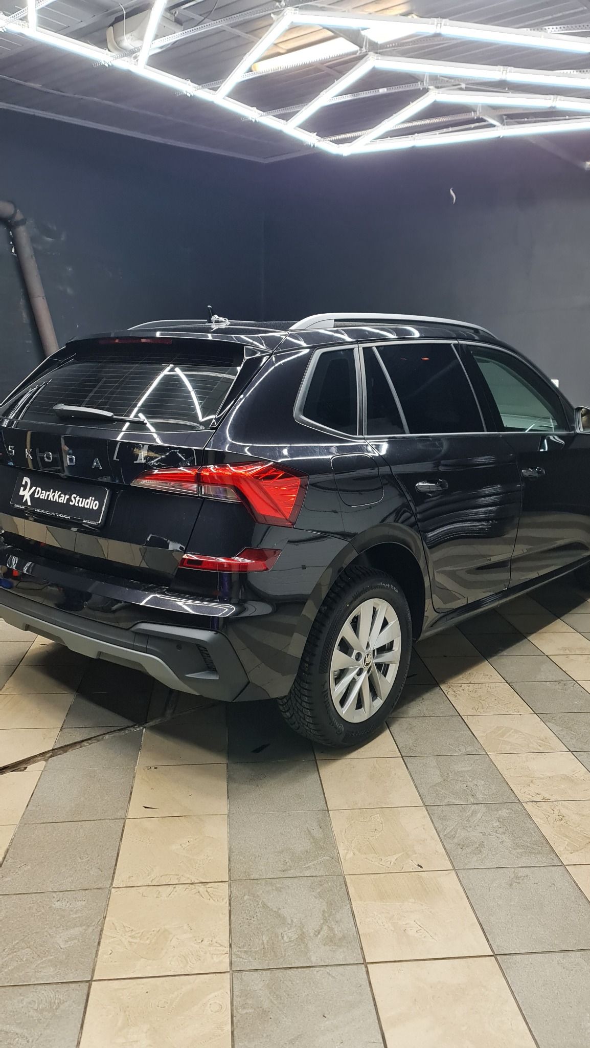 Czarne auto Skoda Kamik w studiu detailingu DarkKar, widok z tyłu, oświetlenie LED na suficie, płytki podłogowe.