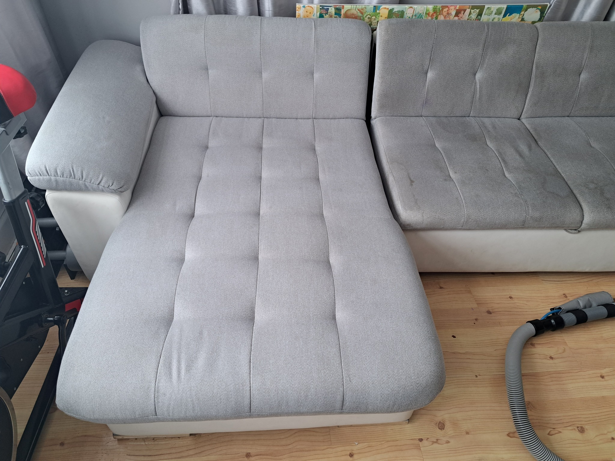 Szara, modułowa kanapa z widocznymi plamami i rurą od odkurzacza na drewnianej podłodze.