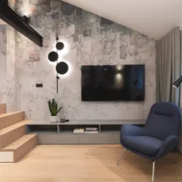 Nowoczesny salon z dekoracyjną ścianą o fakturze betonu, oświetleniem LED w kształcie kuli, drewnianymi schodami z czarnymi balustradami, szarą szafką RTV i niebieskim fotelem.