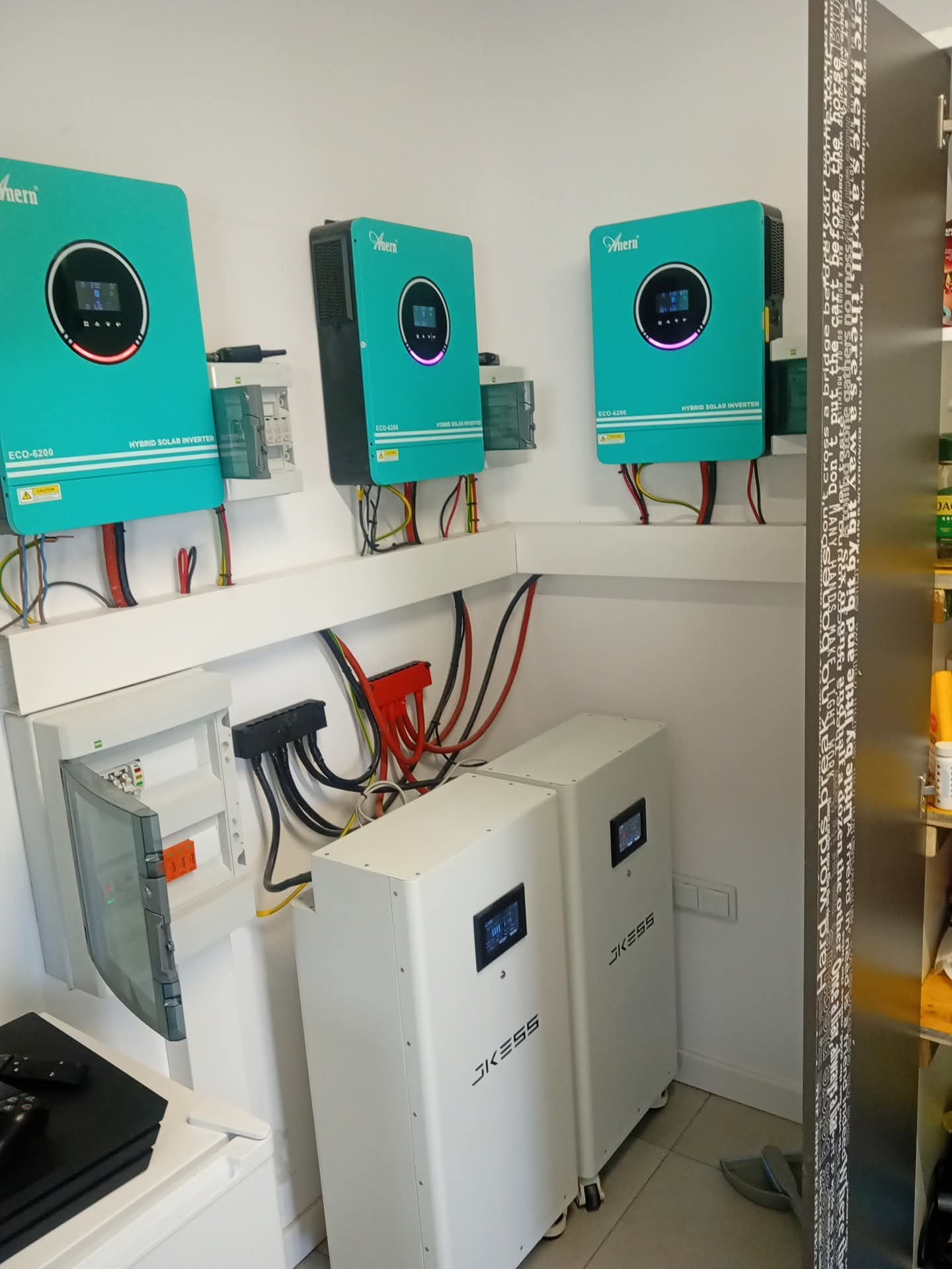 Kompletna instalacja fotowoltaiczna w pomieszczeniu: dwa białe magazyny energii JKESS, trzy turkusowe inwertery Ahern ECO-6200 i ECO-4200, oraz skrzynka elektryczna.