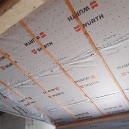 CNG-Uslugi Budowlane - Izolacja poddasza z widocznymi krokwiami i membraną dachową z logo Wurth, widok od dołu.