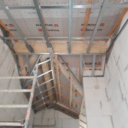 CNG-Uslugi Budowlane - Szkieletowa konstrukcja poddasza z widocznymi elementami drewnianymi i metalowymi profilami, pokryta membraną marki Wurth z drabiny podczas montażu.