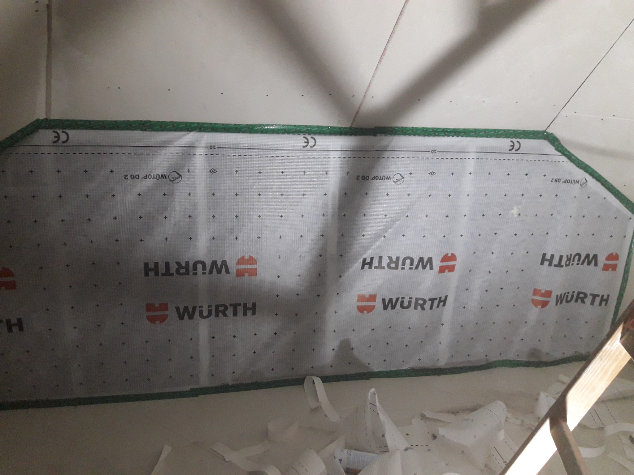 Fragment ściany z zamontowaną membraną paroizolacyjną Wurth WUTOP DB 2, widoczne czarne punkty na membranie, zielone obramowanie i fragment drabiny.