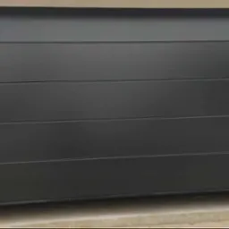 Zamknięta, segmentowa brama garażowa w kolorze antracytowym z poziomymi przetłoczeniami, widoczny fragment posadzki i ościeżnicy.