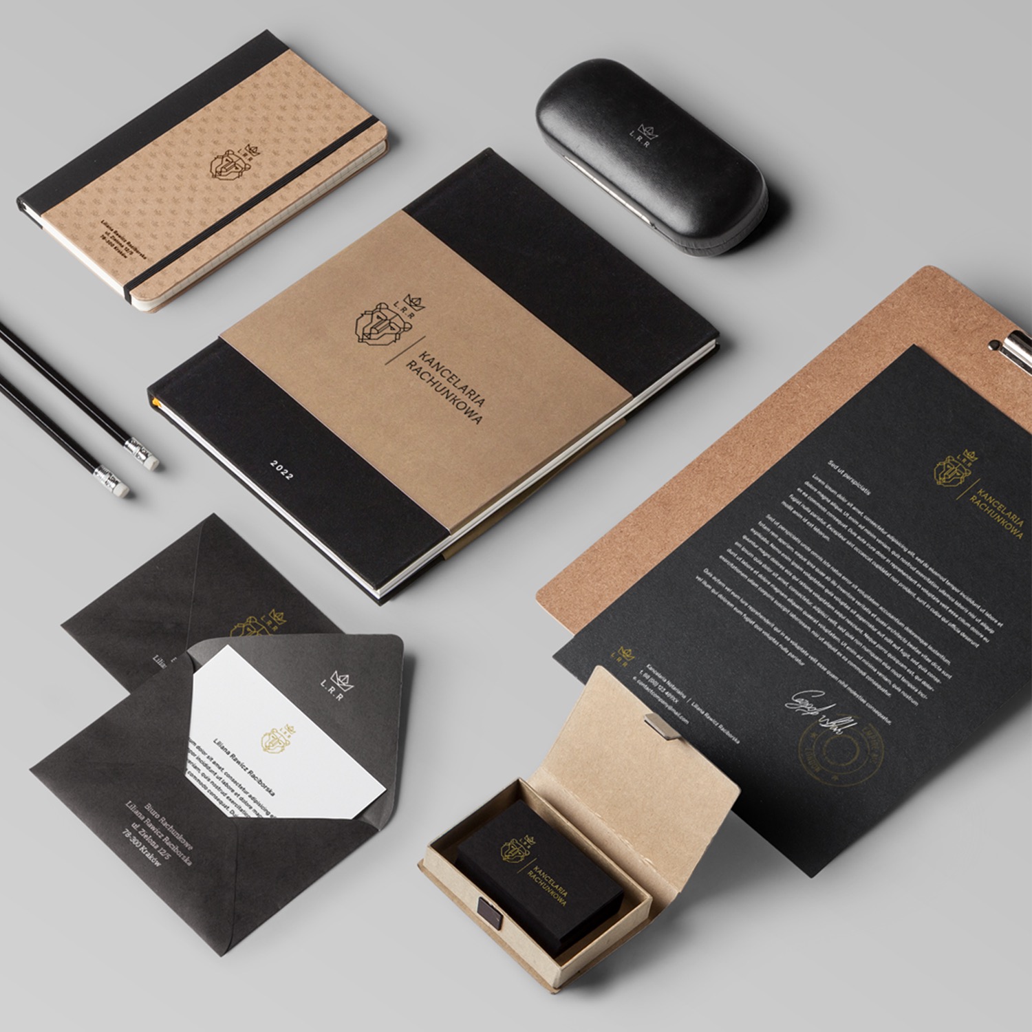 Zestaw materiałów identyfikacji wizualnej dla firmy: notes, teczka z dokumentami, wizytówki w pudełku i koperty z papierem firmowym, wszystko w tonacji czerni, beżu i złota, z eleganckim logo.