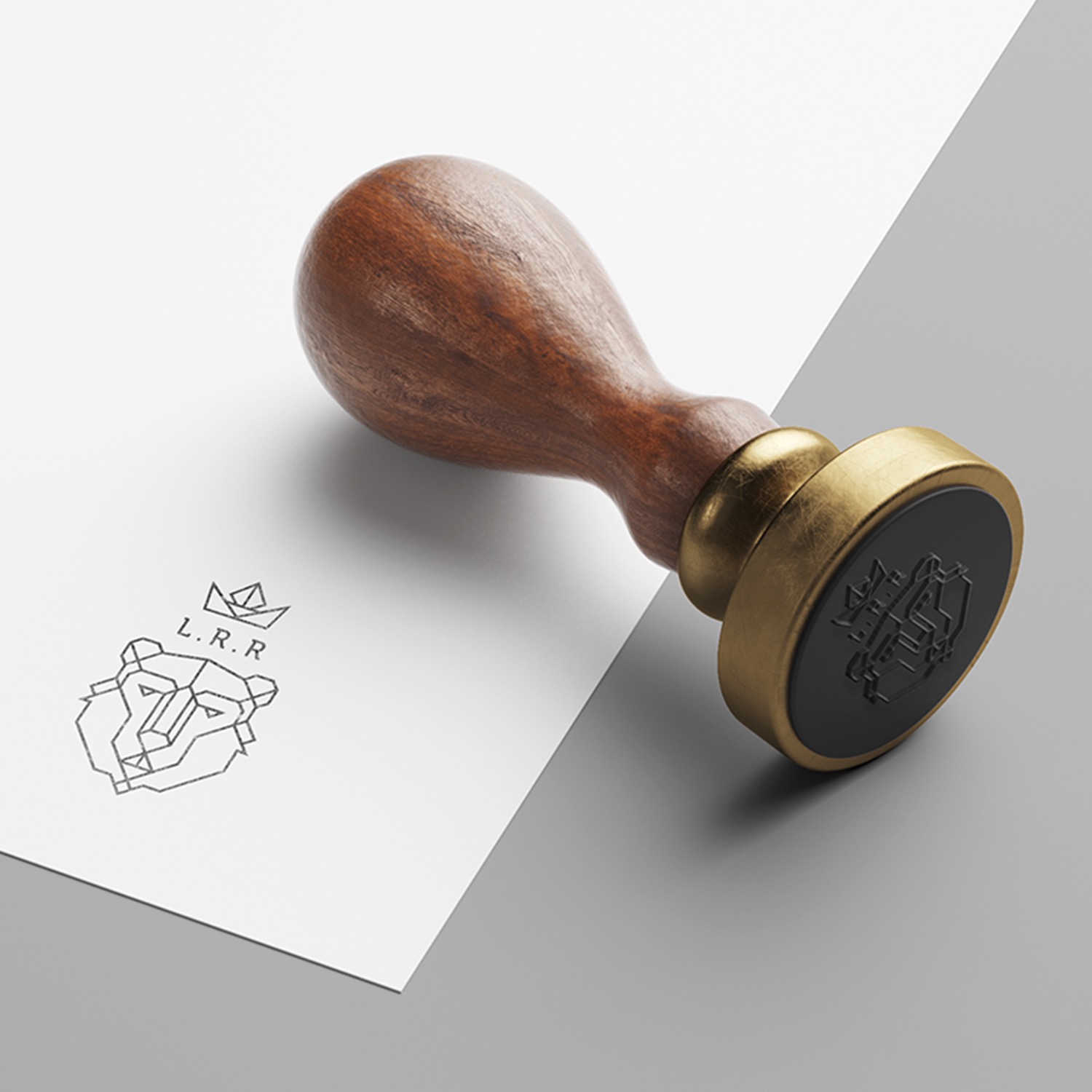 Drewniany stempel z mosiężną obwódką, odbijający minimalistyczny logotyp lwa z koroną na białej kartce, leżącej na szarym tle.