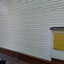 Clean Manager - Czyszczenie elewacji sidingu myjką ciśnieniową. Widoczne zabrudzenia przed i po czyszczeniu, sprzęt do mycia. Ujęcie z dołu, z boku budynku.