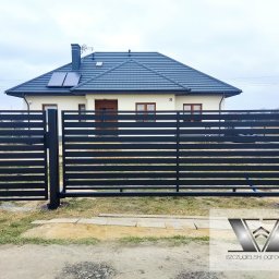 Szczygielski-Ogrodzenia - Nowoczesne, poziome, czarne przęsła ogrodzeniowe na tle domu z szarą dachówką i panelami słonecznymi.