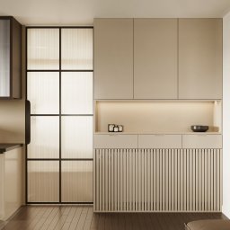 RB VISION SPÓŁKA Z OGRANICZONĄ ODPOWIEDZIALNOŚCIĄ - Minimalistyczna kuchnia w beżach: zabudowa z lamelami, przeszklenie z czarnymi szprosami, drewniana podłoga. Oświetlenie punktowe i subtelne podświetlenie blatu.