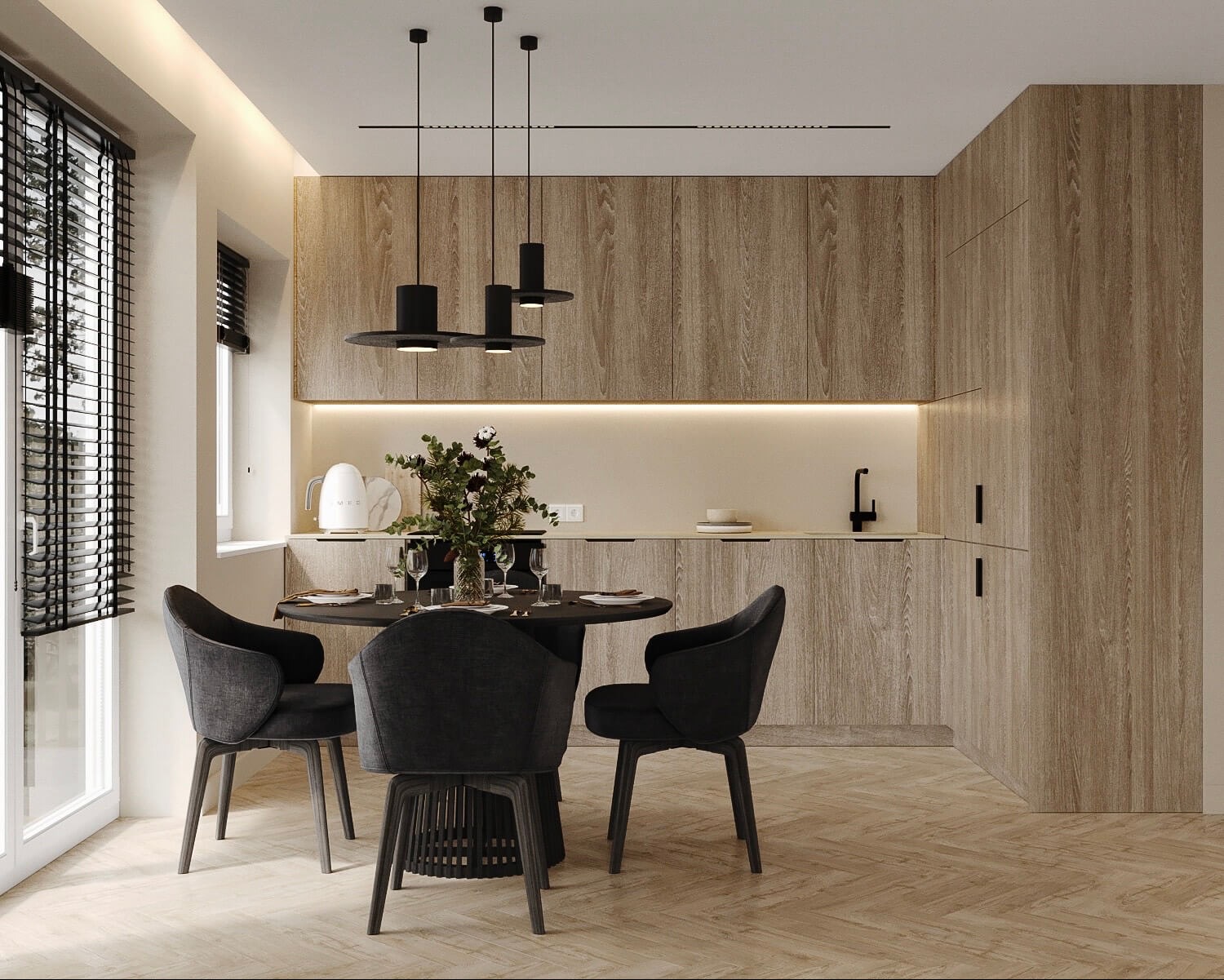 Nowoczesna kuchnia z drewnianymi szafkami, okrągłym stołem i trzema czarnymi lampami wiszącymi, uzupełniona o kwiaty i biały czajnik Smeg.