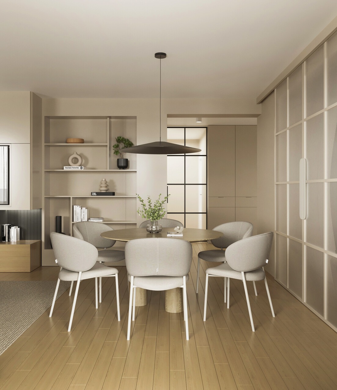 Jasna jadalnia z okrągłym stołem i krzesłami na tle regału z dekoracjami i przeszklonej ściany. Minimalistyczny design, ciepłe oświetlenie, drewniana podłoga.