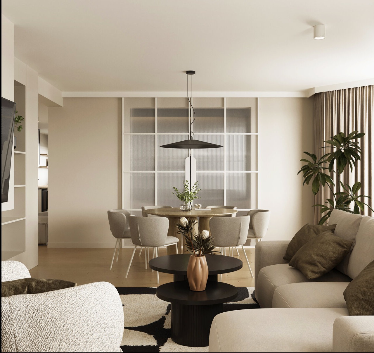 Jasne wnętrze: okrągły stół z krzesłami, sofa z poduszkami, czarno-biały dywan. Nad stołem wisi lampa. Za stołem okno z białymi szprosami.