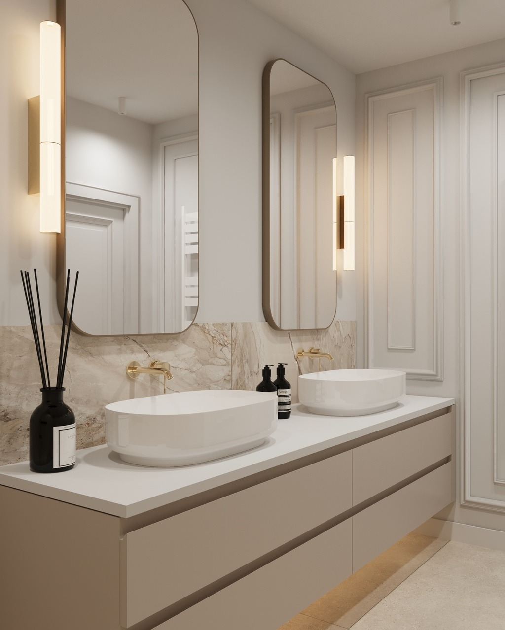 Elegancka łazienka z dwoma owalnymi umywalkami, złotą armaturą i podświetlanymi lustrami. Marmurowe wykończenie ściany i minimalistyczne oświetlenie.