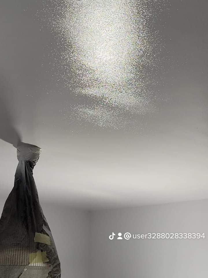 Błyszczący efekt na suficie po malowaniu, widoczne drobinki brokatu, zabezpieczona lampa wisząca folią malarską.