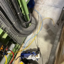 JKW-SYSTEM Jakub Wróblewski - Widok z góry na kable elektryczne ułożone w korycie kablowym, podłączone do urządzenia pomiarowego z manometrem, z widocznymi przewodami i elementami instalacji.