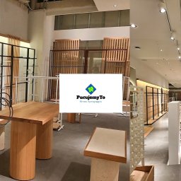 Pucujemyto - Wnętrze sklepu odzieżowego w trakcie sprzątania, widoczne drewniane i metalowe regały, stoły ekspozycyjne oraz logo firmy sprzątającej PucujemyTo nałożone na zdjęcie.