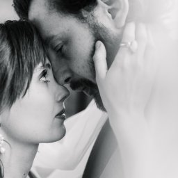 Maciej Wadas Fotografia - Czarno-białe zbliżenie na twarze pary młodej, dotykających się czołami, z pierścionkiem zaręczynowym na dłoni mężczyzny i delikatnym światłem z prawej strony.