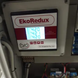 Panel sterowania EkoRedux w szarej obudowie, wyświetlający wartości 420 i 421, z widocznymi przewodami i elementami instalacji elektrycznej w tle.