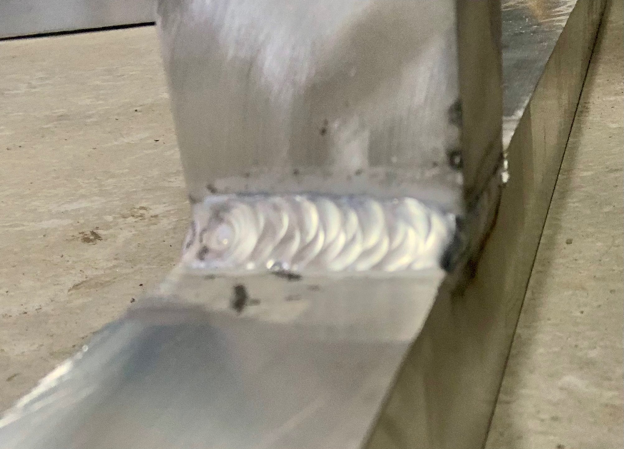 Metalowy element konstrukcyjny z widocznym, świeżym spawem o charakterystycznej fakturze, ujęcie z bliska.