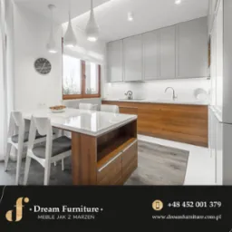 Jasna kuchnia z drewnianymi elementami: białe szafki górne, drewniane szafki dolne, biały blat, stół z wyspą i krzesła w stylu skandynawskim, widoczne oświetlenie punktowe i wiszące lampy.