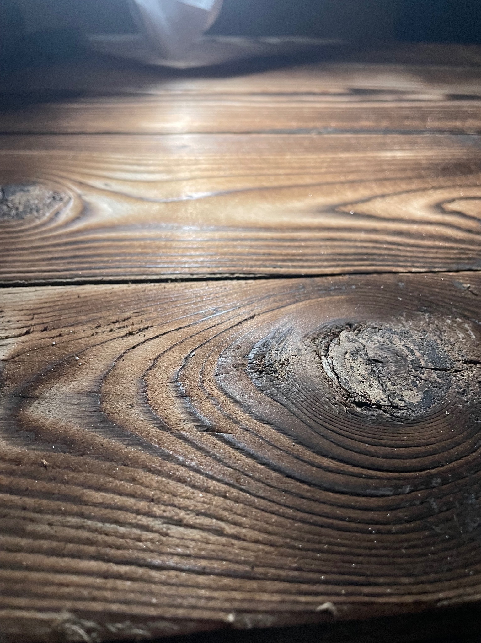 Opalona deska z wyraźnym usłojeniem i sękiem, oświetlona od góry.