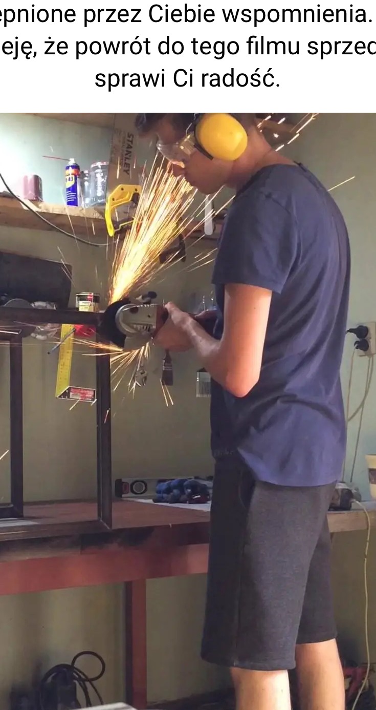 Pracownik w okularach ochronnych i słuchawkach tnący metalową konstrukcję szlifierką kątową, iskry w warsztacie.