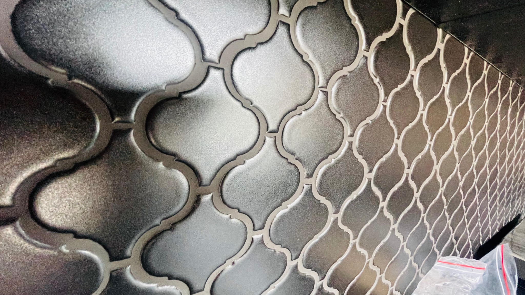 Mozaika w odcieniach szarości o marokańskim wzorze, ułożona na ścianie w Katowicach, z widocznymi delikatnymi refleksami światła.