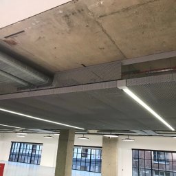 BUILDERS GROUP SPÓŁKA Z OGRANICZONĄ ODPOWIEDZIALNOŚCIĄ - Sufit podwieszany rastrowy z oświetleniem LED w nowoczesnym biurze, widoczne instalacje wentylacyjne pod surowym betonowym stropem.