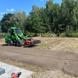 RoboExpert - Zielony traktor z glebogryzarką przygotowuje teren pod trawnik, widoczny pracownik i wygładzona ziemia z charakterystycznym wzorem