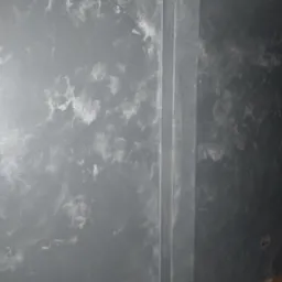 Ściana po nałożeniu szarej farby z efektem dekoracyjnym, widoczne białe przetarcia i pionowa listwa przy ścianie, fragment podłogi z parkietu.