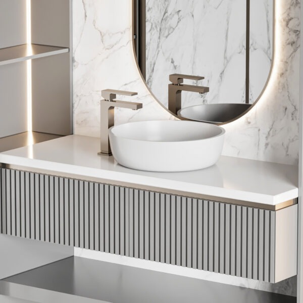 Nowoczesna łazienka z umywalką nablatową, baterią w kolorze szczotkowanego złota i podświetlanym lustrem na tle marmurowej ściany.