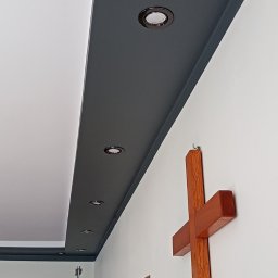 MarHor Renovations - Pomalowany na szaro fragment sufitu z zamontowanymi punktowymi lampami LED, widoczny drewniany krzyż na ścianie i fragment drabiny malarskiej.