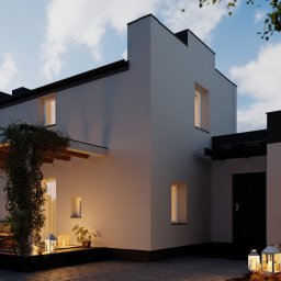 BUDOWNICTWO I ZIELEŃ - Nowoczesny dom jednorodzinny z płaskim dachem oświetlony wieczornym światłem, z tarasem porośniętym bluszczem i dekoracyjnymi lampionami na brukowanym podjeździe.