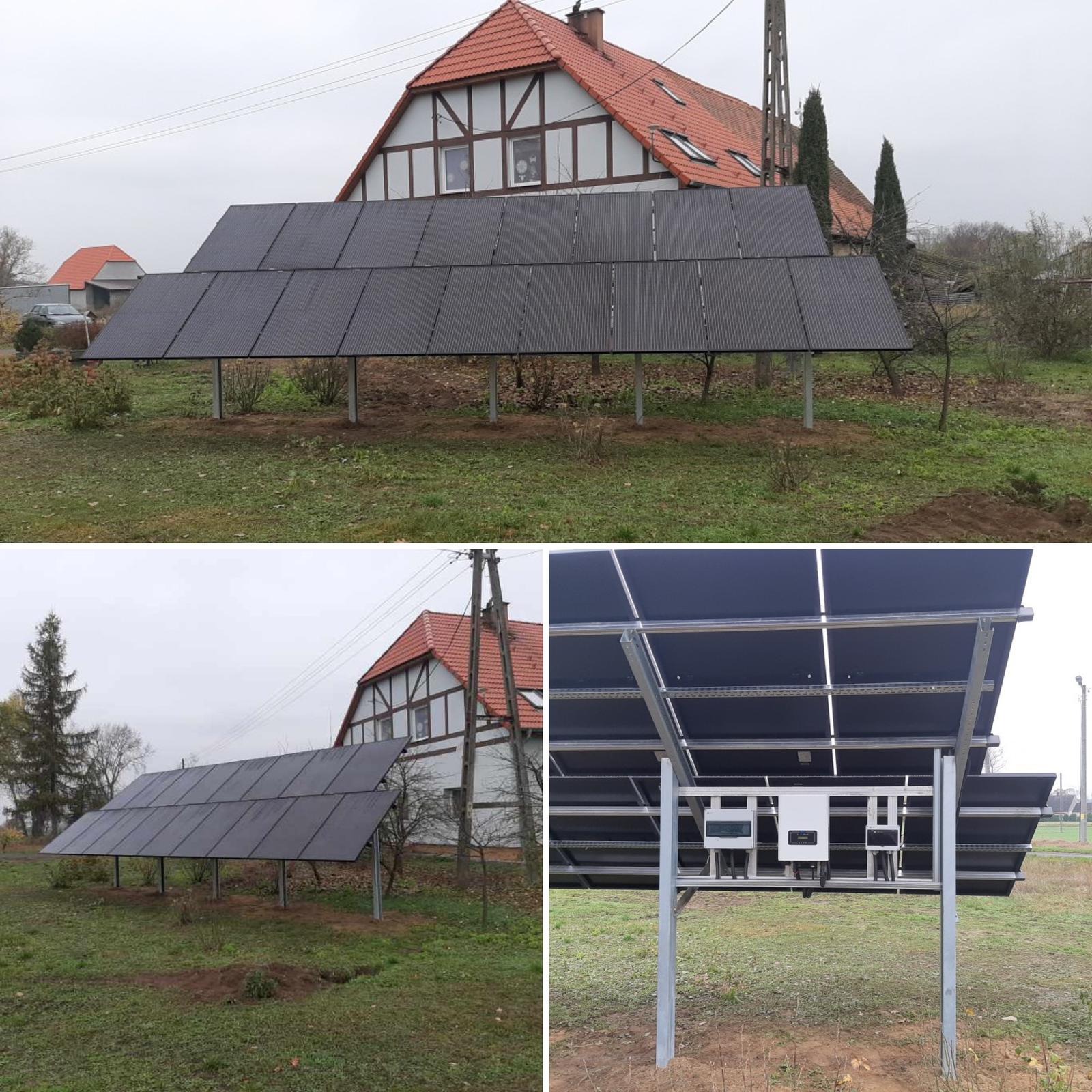 Instalacja fotowoltaiczna na metalowej konstrukcji w ogrodzie, z widocznymi inwerterami pod panelami i domem w tle.